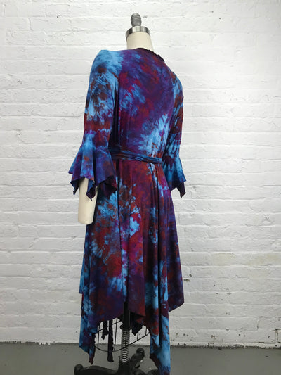 The Flamenco Wrap Dress in Falling Berries is a mix of blues and violets has an asymmetrical hemline and fitted elbow length sleeves that end in a delightful flounce. Wrap styling lends itself to an easy fit and a flattering V-neckline and pockets - back view